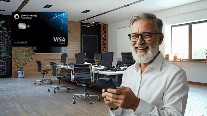 A happy older man with gray hair and glasses is using his smartphone in a bright, stylish office. A Chase Freedom Visa Signature credit card is digitally overlaid in the top left corner.