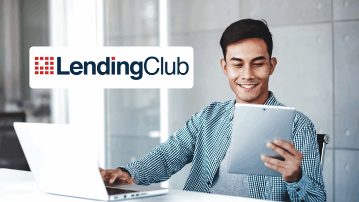 A young man in a checkered shirt is sitting at a desk, smiling while using a tablet and a laptop. The LendingClub logo is displayed in the upper left corner.