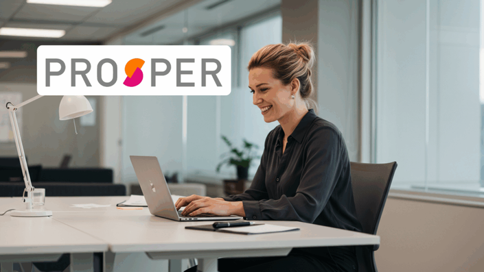 Professional woman working on a laptop in a bright office space, smiling, with the Prosper logo displayed.