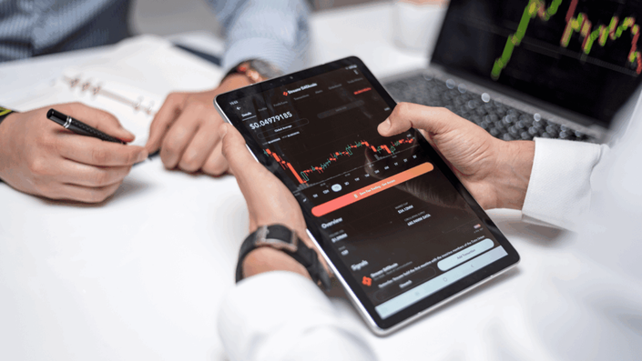 A person intently analyzes cryptocurrency price charts and financial data displayed on a modern tablet, illustrating the focused research involved in digital currency investment.
