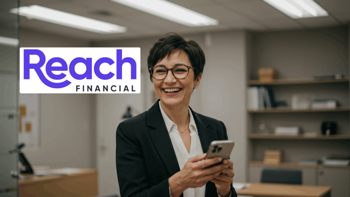 Smiling businesswoman with glasses holding a smartphone in an office, with the Reach Financial logo shown prominently in the foreground.